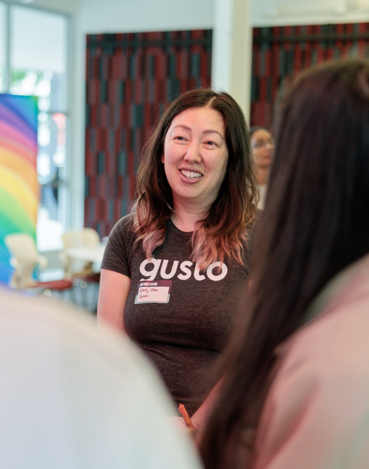 woman wearing a gusto shirt smiling while talking with other women